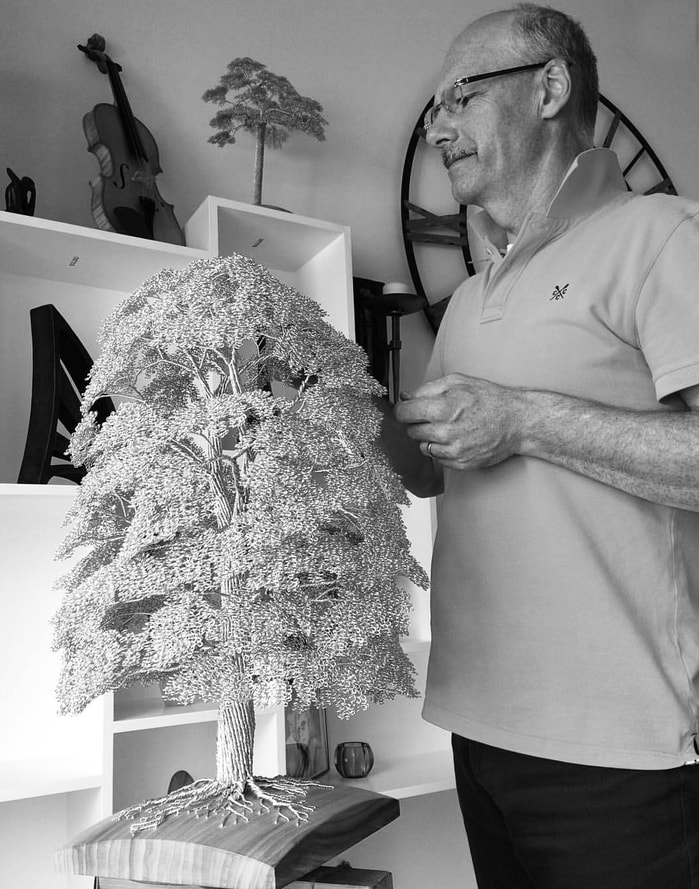 Artist Clive Maddison working on a wire tree sculpture. Black and white image